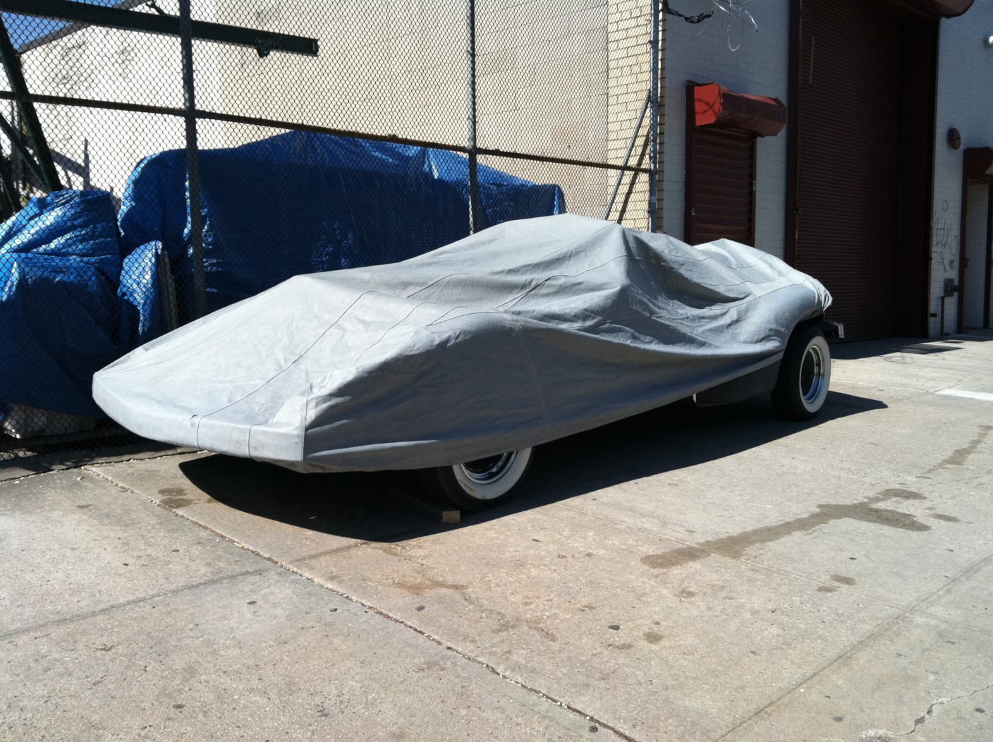 An old sports car covered with a tarp