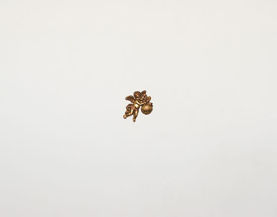 A small plastic gold cherub on a white wall