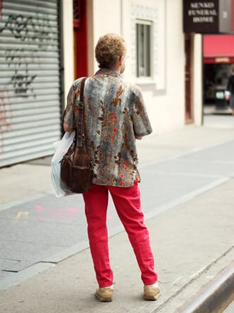Portrait of a person on a sidewalk, with an animal print shirt and red pants