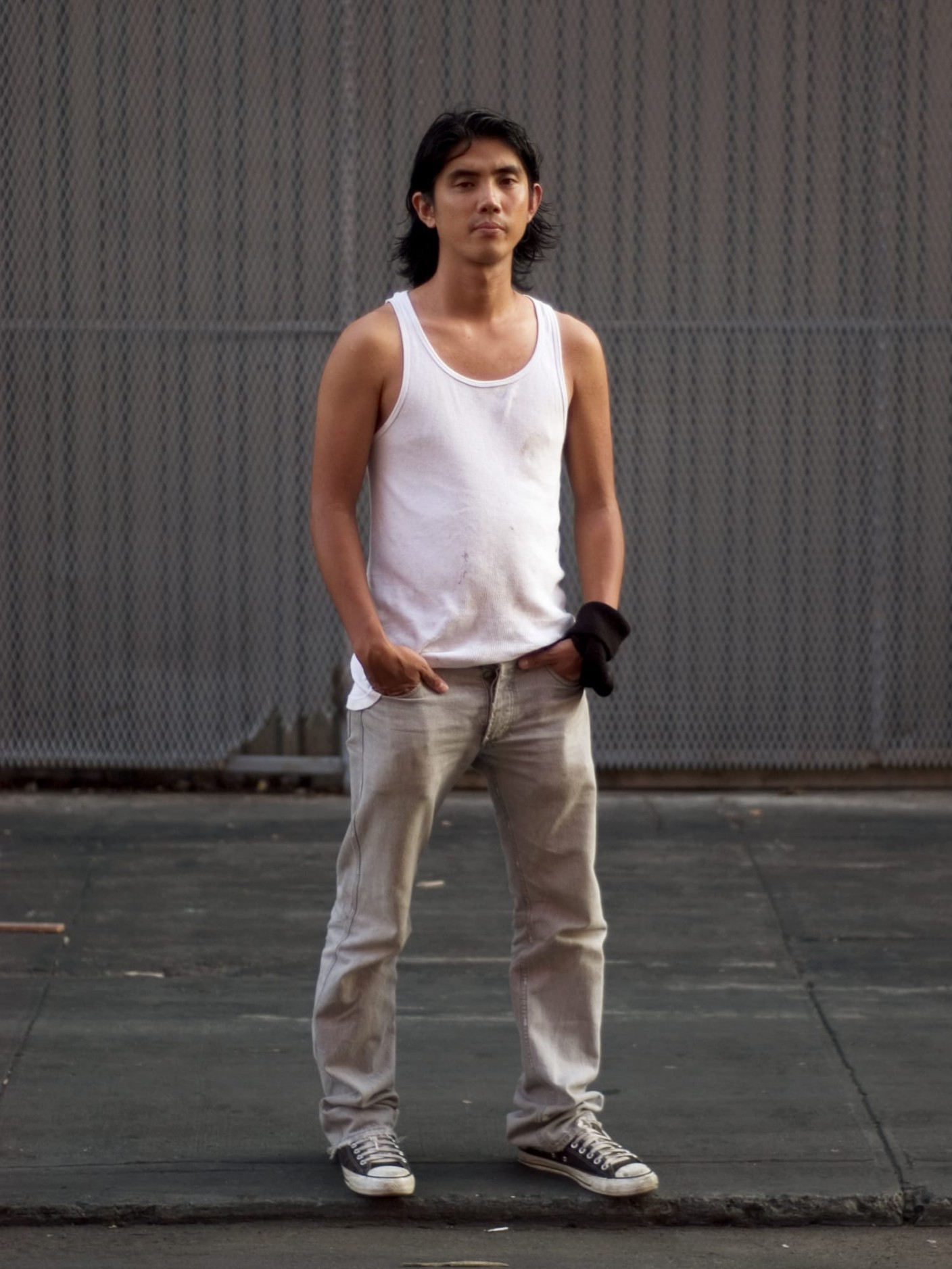 Portrait of a person in an all gray setting, wearing a white tank top and light gray pants