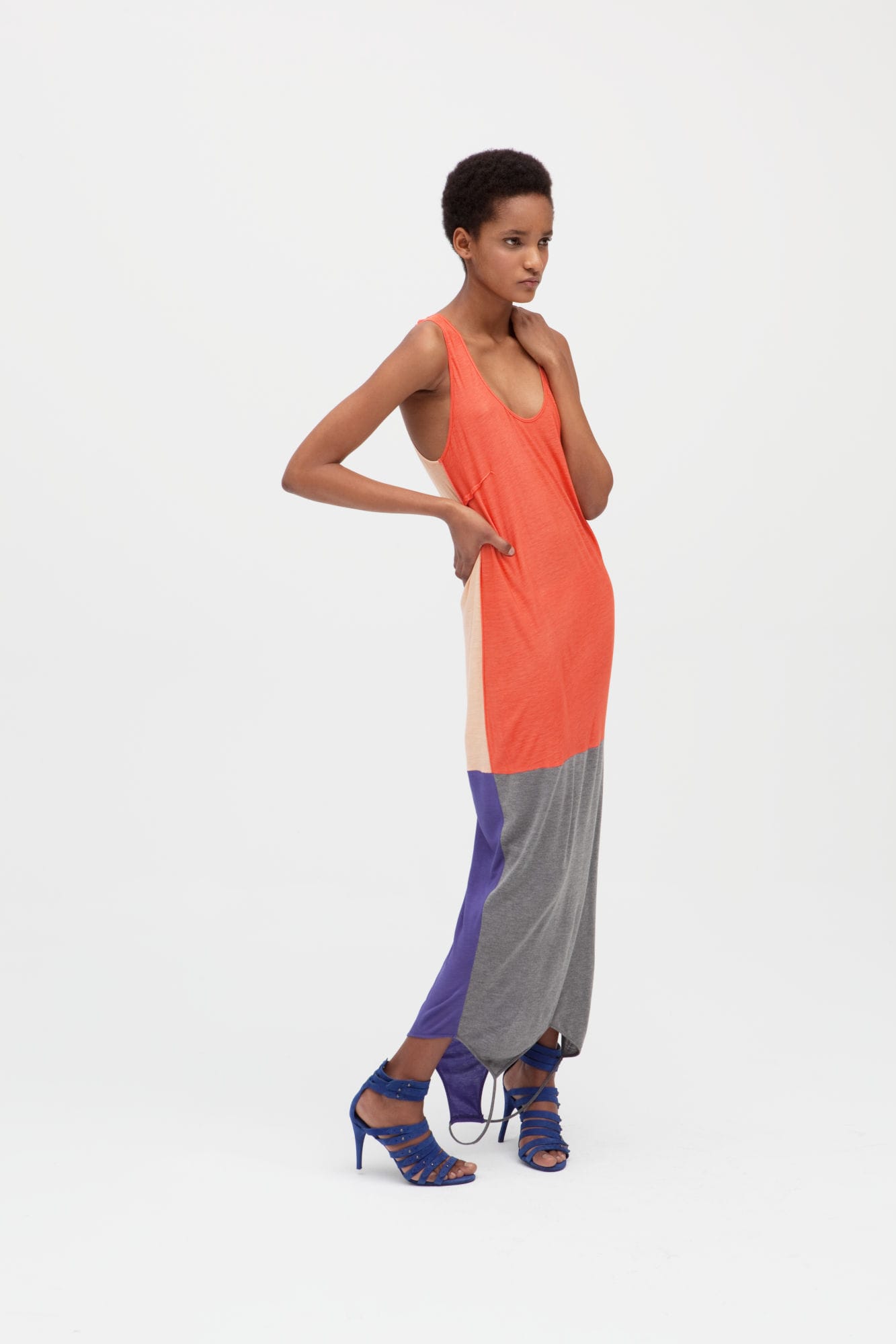Woman wearing a long invertible dress made of 4 panels in orange, gray, purle, and beige.